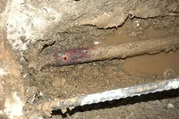 Copper pipe exposed in a wet concrete-floor trench