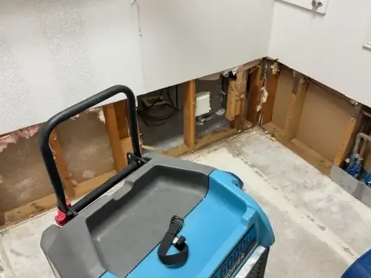 Dehumidifier beside flood-cut drywall in a lower-level room