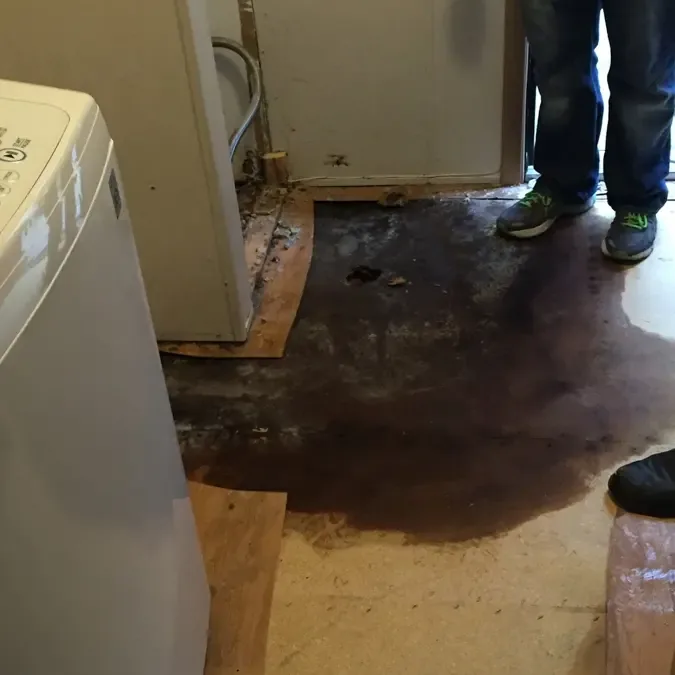 Water across a laundry floor next to a washing machine