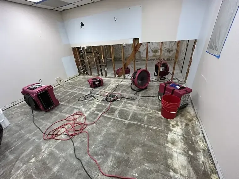 Floor fans and a dehumidifier operating in a stripped room