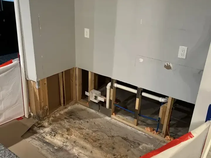 Lower drywall removed to expose kitchen wall framing and plumbing