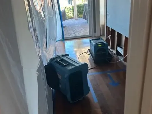 Dehumidifier and air mover beside opened walls in a narrow hallway