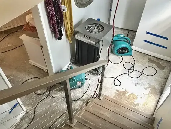 Dehumidifier and air movers beside a stair landing