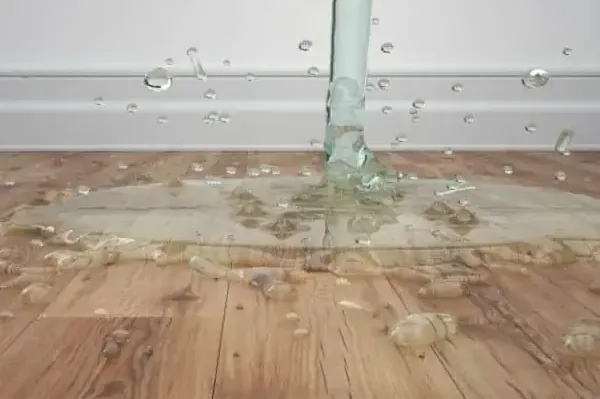 Water splashing onto a wood-pattern floor beneath a supply pipe