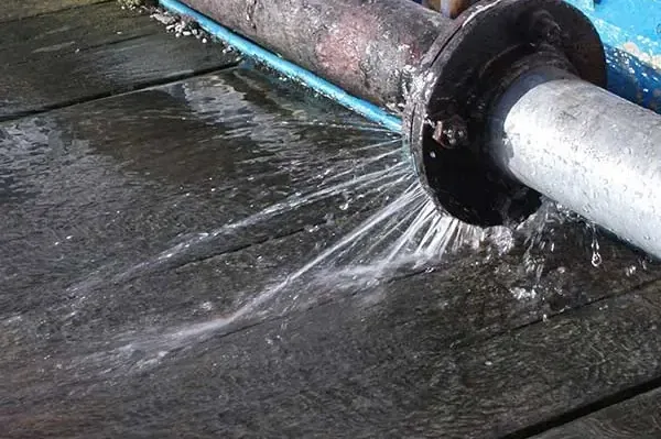 Water spraying from a split pipe joint onto a wet floor
