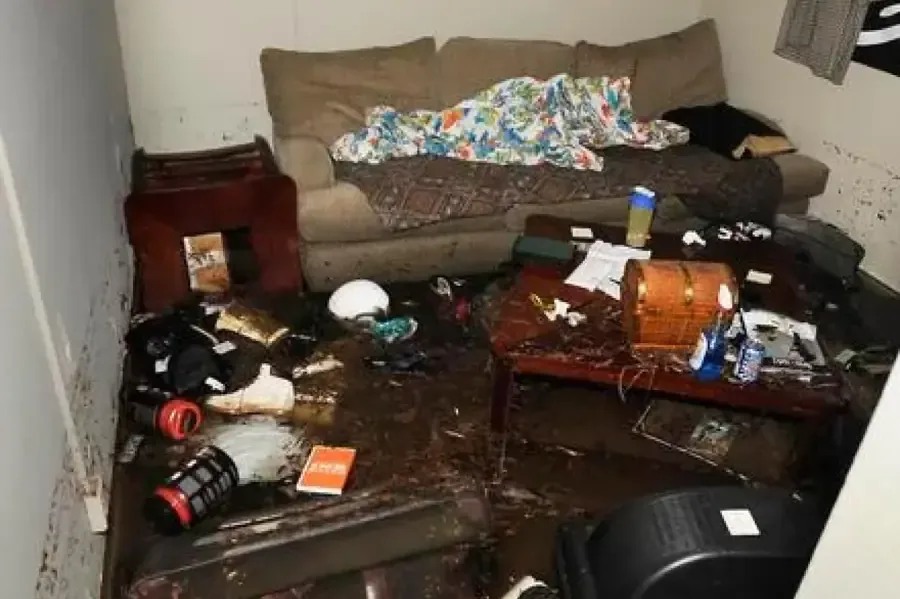 Mud and soaked household belongings across a flood-affected living room